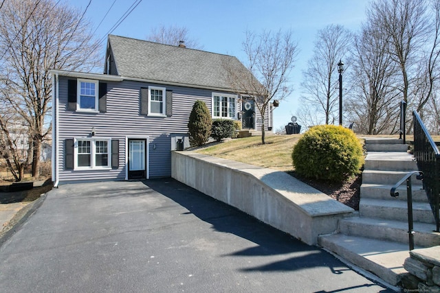 view of front facade with driveway and a shingled roof