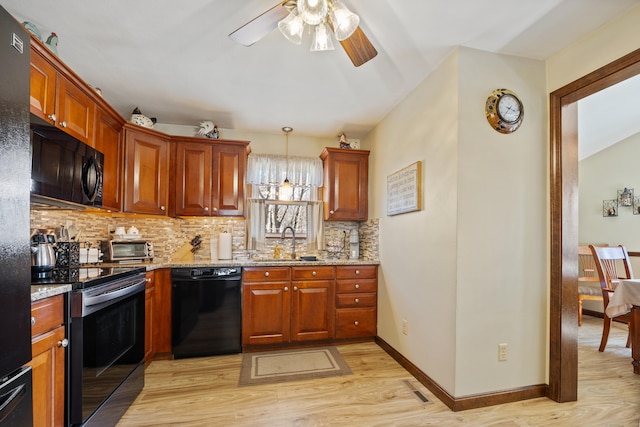 kitchen featuring light wood finished floors, visible vents, black appliances, and a sink