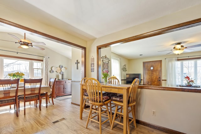 dining space with vaulted ceiling, light wood-style flooring, baseboards, and visible vents