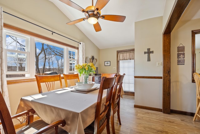 dining room featuring a ceiling fan, light wood-type flooring, baseboards, and vaulted ceiling