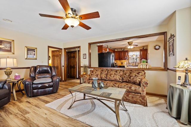 living room featuring baseboards, light wood-style flooring, and a ceiling fan