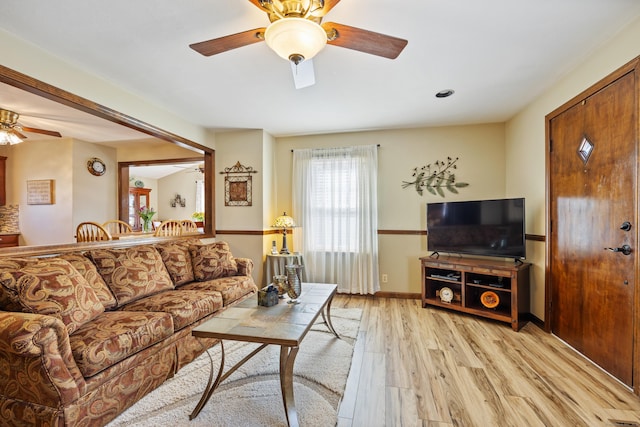 living area with baseboards, light wood-style flooring, and a ceiling fan