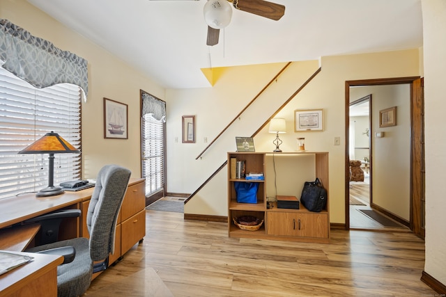 office space featuring a ceiling fan, light wood-style floors, and baseboards