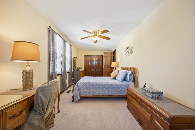 bedroom featuring a ceiling fan, visible vents, and light carpet