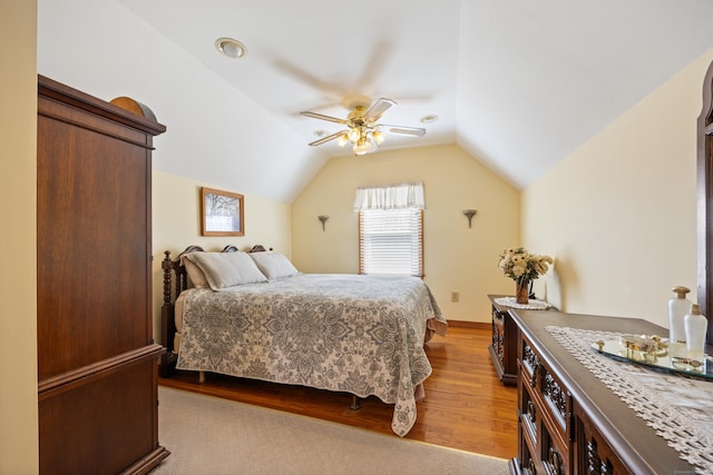 bedroom with ceiling fan, lofted ceiling, and wood finished floors