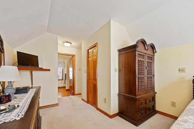 bedroom with lofted ceiling, baseboards, and light carpet