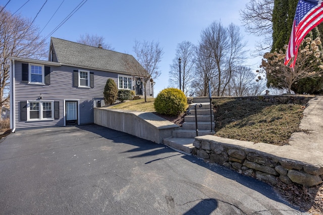 view of front of property with roof with shingles and driveway