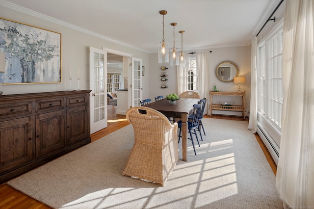 dining space with french doors, light wood-style floors, crown molding, and a baseboard radiator