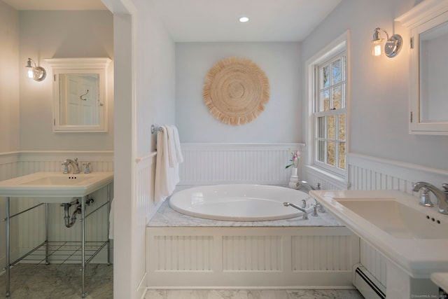 full bathroom with two sinks, a baseboard radiator, recessed lighting, wainscoting, and a garden tub