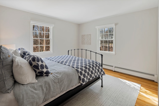 bedroom with wood finished floors and a baseboard radiator