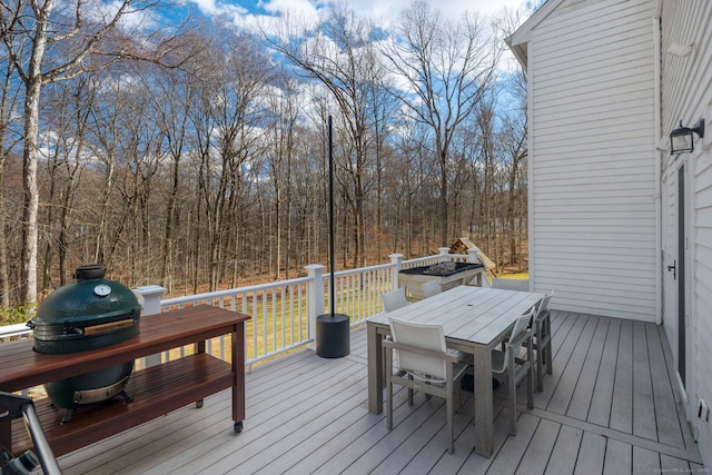 deck featuring outdoor dining space and a view of trees