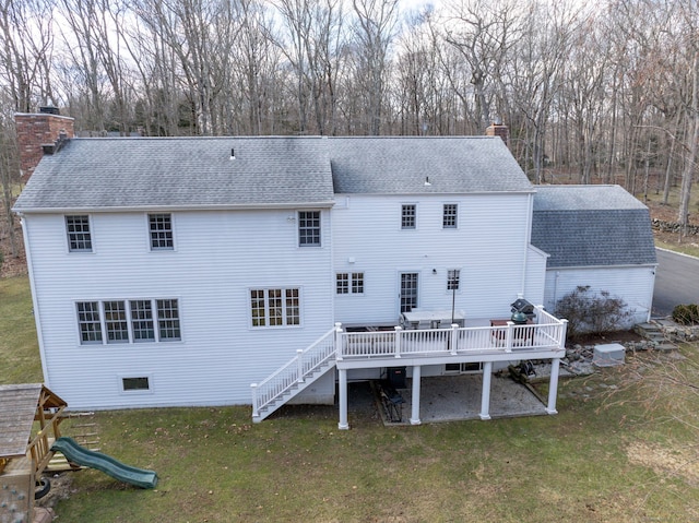 back of house featuring a yard, a chimney, and a shingled roof