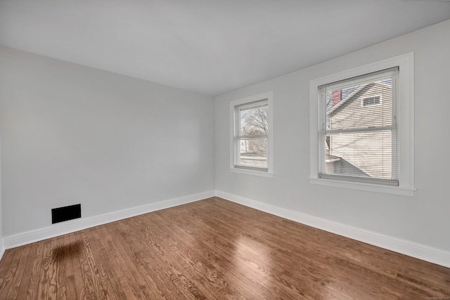 spare room with baseboards and wood finished floors