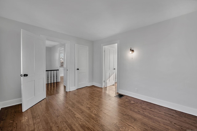 empty room featuring visible vents, baseboards, and wood finished floors