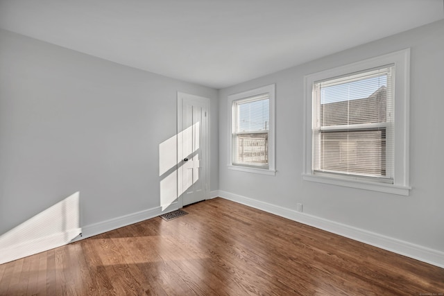 unfurnished room featuring visible vents, baseboards, and dark wood-style floors