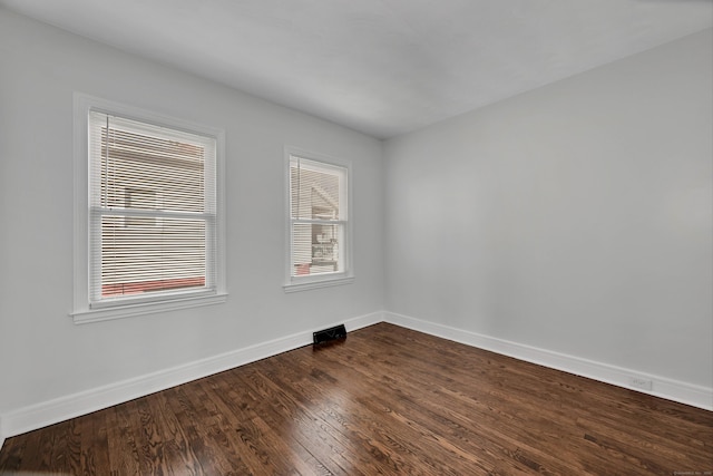 empty room featuring baseboards and dark wood-style flooring