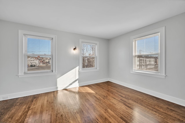 spare room featuring baseboards and wood finished floors