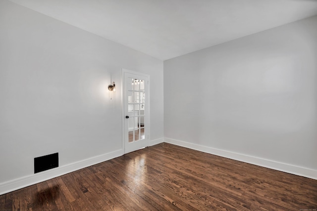 spare room featuring dark wood-style floors and baseboards