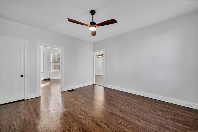 empty room with dark wood-type flooring, visible vents, baseboards, and ceiling fan