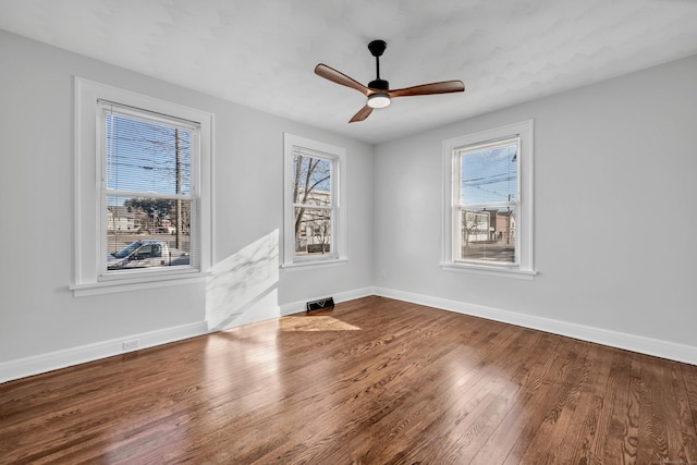 empty room with visible vents, wood finished floors, baseboards, and ceiling fan