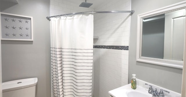 full bath featuring a sink, toilet, and a tile shower