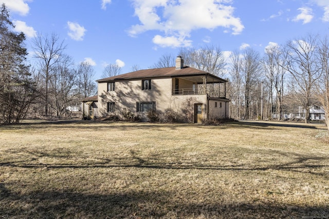 view of home's exterior featuring a lawn, a chimney, and a balcony