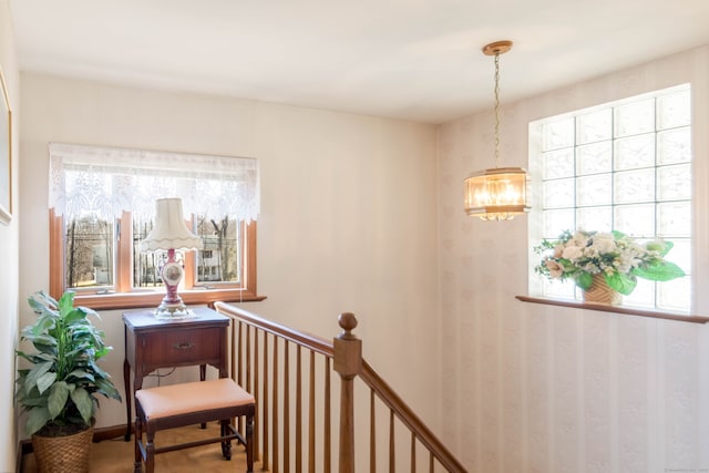 corridor featuring an upstairs landing and a chandelier