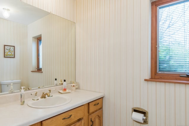 bathroom featuring toilet, wallpapered walls, and vanity