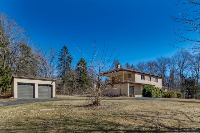 view of front of home with an outbuilding, a garage, stucco siding, and a front yard