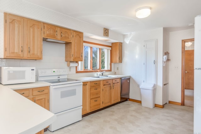 kitchen featuring white appliances, baseboards, wallpapered walls, a sink, and light countertops