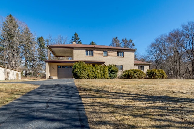 view of front facade with aphalt driveway, a garage, a chimney, and a front yard