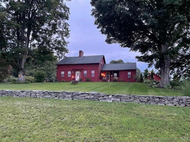 back of property with a chimney and a yard