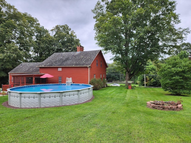 outdoor pool featuring a yard and a fire pit