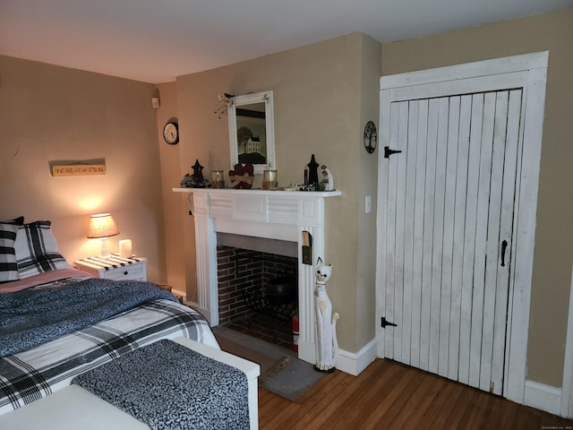 bedroom with a fireplace, baseboards, and wood finished floors