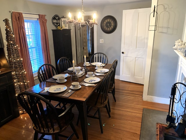 dining room with a notable chandelier, baseboards, and wood finished floors