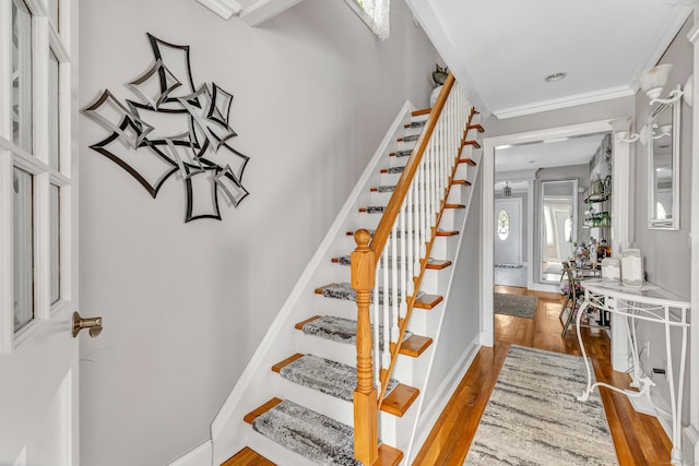 stairway with baseboards, wood finished floors, and crown molding