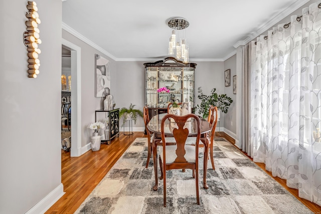 dining space with baseboards, light wood-style floors, and crown molding