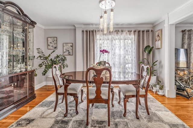 dining room with a notable chandelier, crown molding, baseboards, and wood finished floors