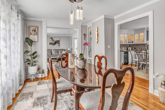 dining room featuring wine cooler, crown molding, and light wood finished floors