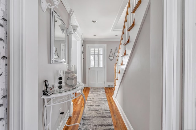 entryway with stairway, baseboards, visible vents, crown molding, and light wood-type flooring