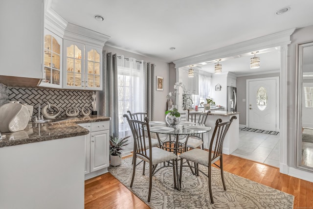 dining space with light wood finished floors and ornamental molding