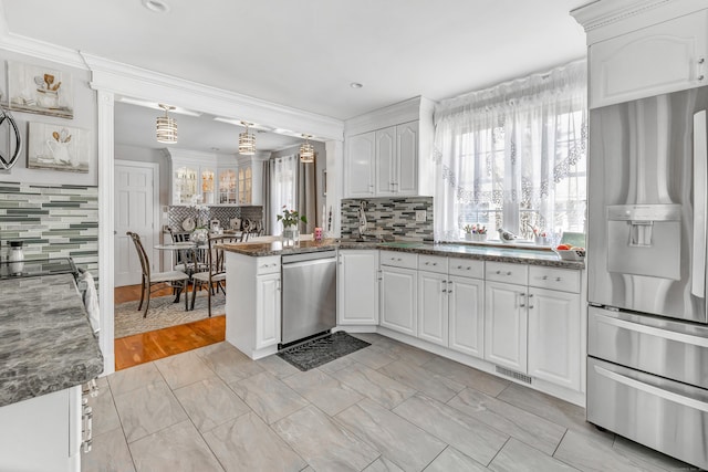 kitchen with tasteful backsplash, visible vents, appliances with stainless steel finishes, a peninsula, and white cabinets