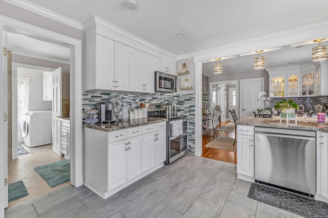 kitchen with dark stone counters, appliances with stainless steel finishes, white cabinets, crown molding, and decorative backsplash