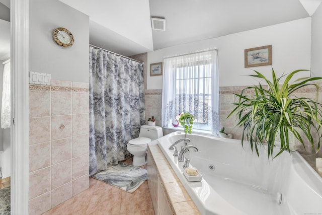 bathroom with visible vents, toilet, a jetted tub, and tile walls