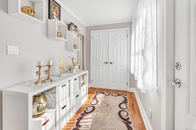 interior space featuring crown molding, baseboards, and light wood-type flooring