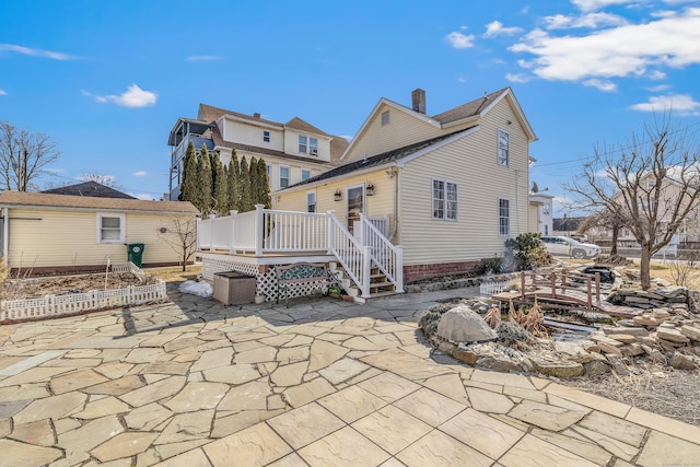 back of house with a patio, a deck, and a chimney