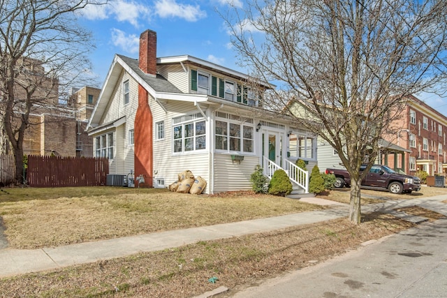 view of front of home with entry steps, fence, cooling unit, a front yard, and a chimney