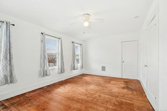 spare room featuring hardwood / wood-style flooring, baseboards, visible vents, and ceiling fan