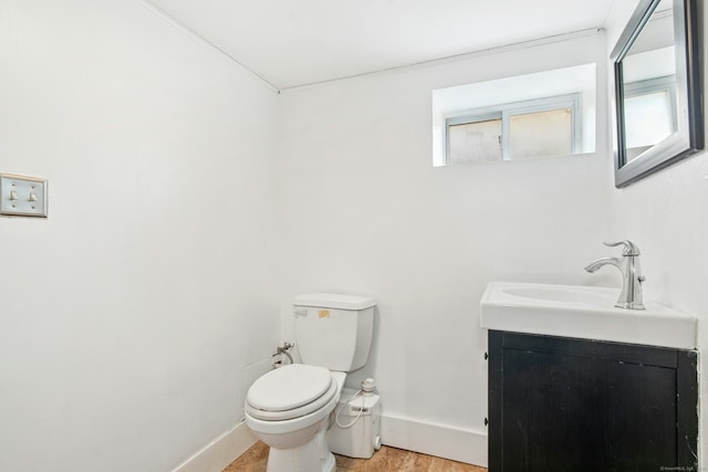 half bath featuring toilet, vanity, and baseboards