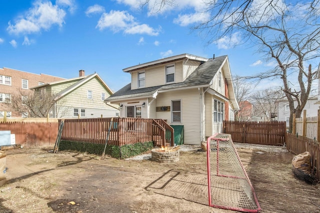 rear view of house featuring a wooden deck, a fenced backyard, and an outdoor fire pit